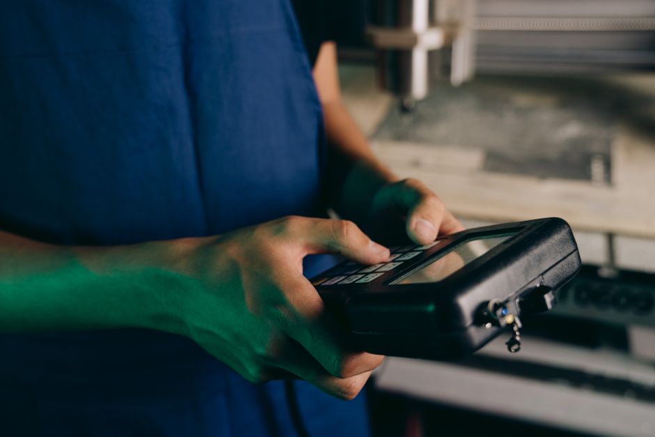 Close-up of technician using a handheld control device in a manufacturing setting