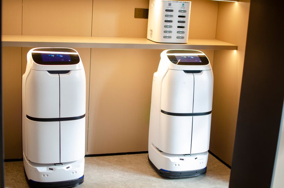Two white robotic delivery systems located in a modern indoor room with soft lighting